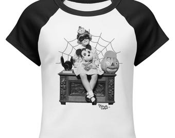 May include: A white raglan t-shirt with black sleeves featuring a black and white graphic of a child in a mask sitting on a carved wooden chest. The child holds a Mickey Mouse toy next to a jack-o'-lantern and a spiderweb. Text reads The Cobweb Casket.