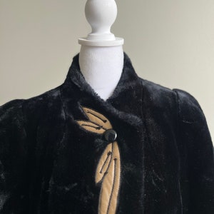 May include: A black faux fur jacket with a brown leather accent and a single button closure.
