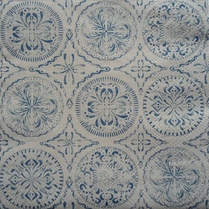 May include: White paper napkin with a repeating pattern of blue circular designs. Each circle features a floral or geometric motif, with a scalloped edge. The design is reminiscent of vintage or bohemian styles.