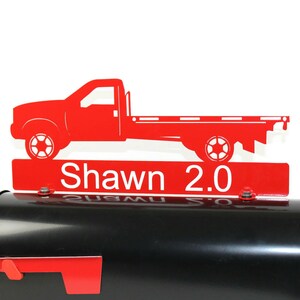 Pode incluir: Tope de caixa de correio de metal vermelho com uma silhueta de caminh&atilde;o de plataforma vermelha e o texto "Shawn 2.0".