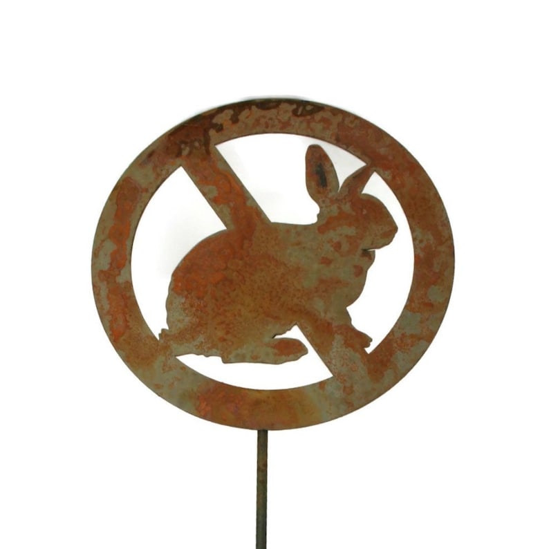 May include: A rusty metal garden stake with a round sign that says "No Rabbits" with a silhouette of a rabbit inside the circle. The sign is crossed out.