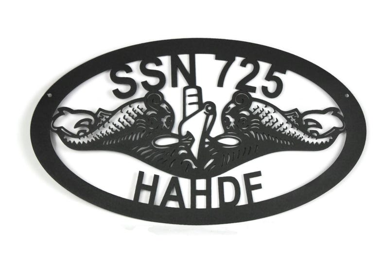 Puede incluir: Un letrero de pared ovalado de metal negro con un dise&ntilde;o recortado de la insignia de guerra submarina, que incluye dos delfines flanqueando la proa de un submarino. El texto SSN 725 est&aacute; sobre la insignia y el texto HAHDF est&aacute; debajo.