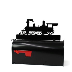 May include: A black metal mailbox with a red flag and a decorative black silhouette of a steam train on top. The mailbox is a classic design, perfect for a home or business.