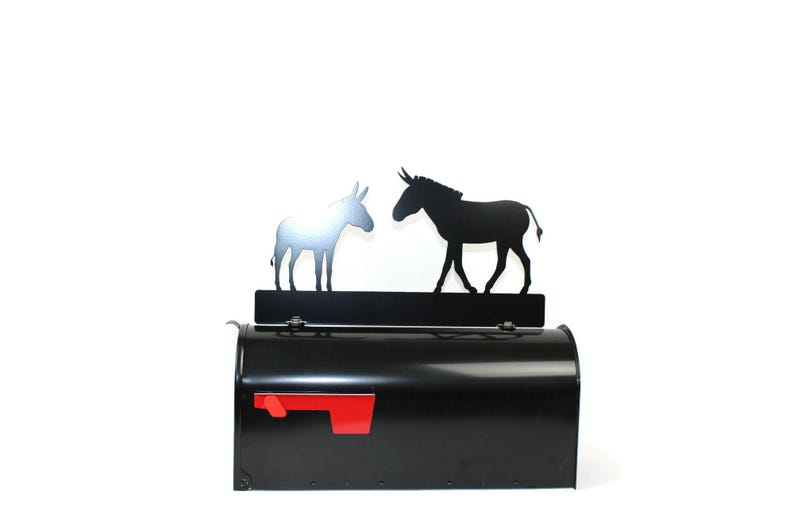 Puede incluir: Buz&oacute;n negro con una bandera roja y una silueta met&aacute;lica de dos burros enfrentados en la parte superior.