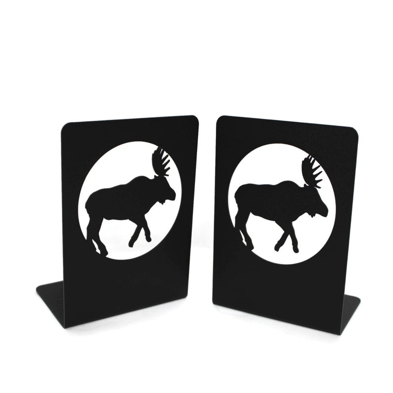 May include: A pair of black metal bookends featuring a moose silhouette in a circle. The bookends are a decorative and functional addition to any bookshelf.