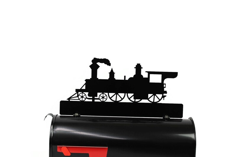 May include: Black metal train silhouette mailbox topper. The topper features a detailed outline of a classic steam engine with smoke billowing from the smokestack. The mailbox is black with a red flag.