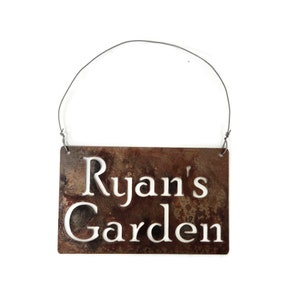 This is a custom metal sign with two holes cut in the top corners. Wire is attached to the holes for hanging.