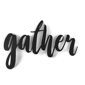 May include: Black metal wall decor with the word "gather" written in a cursive font.