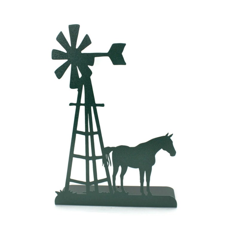 Op de afbeelding: Een groene metalen silhouet van een windmolen en een paard. De windmolen heeft een hoge toren met een ladder en een propeller met drie bladen. Het paard staat naast de windmolen.