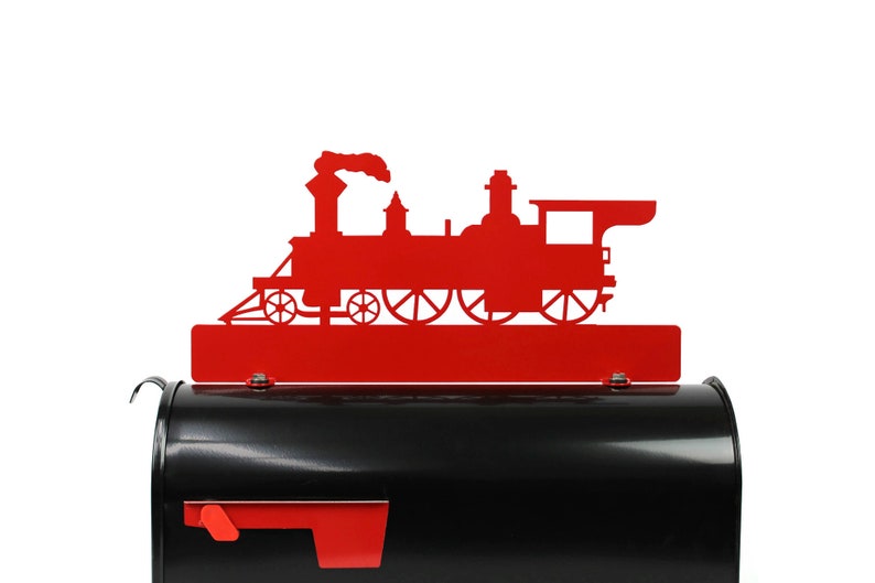 May include: A red metal train silhouette decorates a black mailbox. The train is a classic steam engine design, with a smokestack and multiple wheels. The mailbox has a red flag and a curved handle.