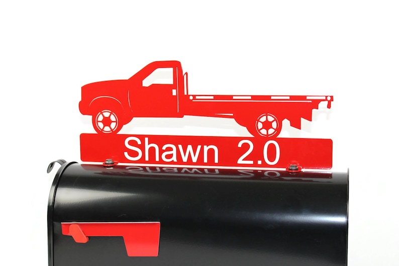 Pode incluir: Tope de caixa de correio de metal vermelho com uma silhueta de caminhonete vermelha e o nome "Shawn 2.0" em um fundo branco.