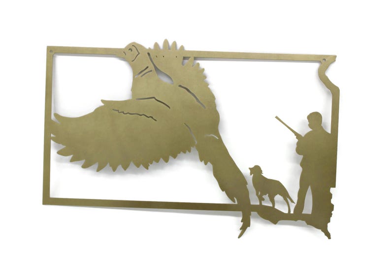 May include: A brass-colored metal wall art piece depicting a pheasant in flight, a hunter with a rifle, and a dog, all within the outline of a state. The artwork is a silhouette style.