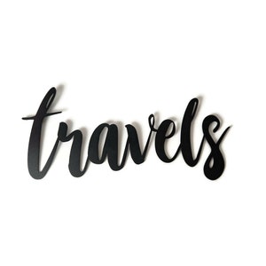 May include: Black metal wall decor with the word "travels" written in a cursive font.