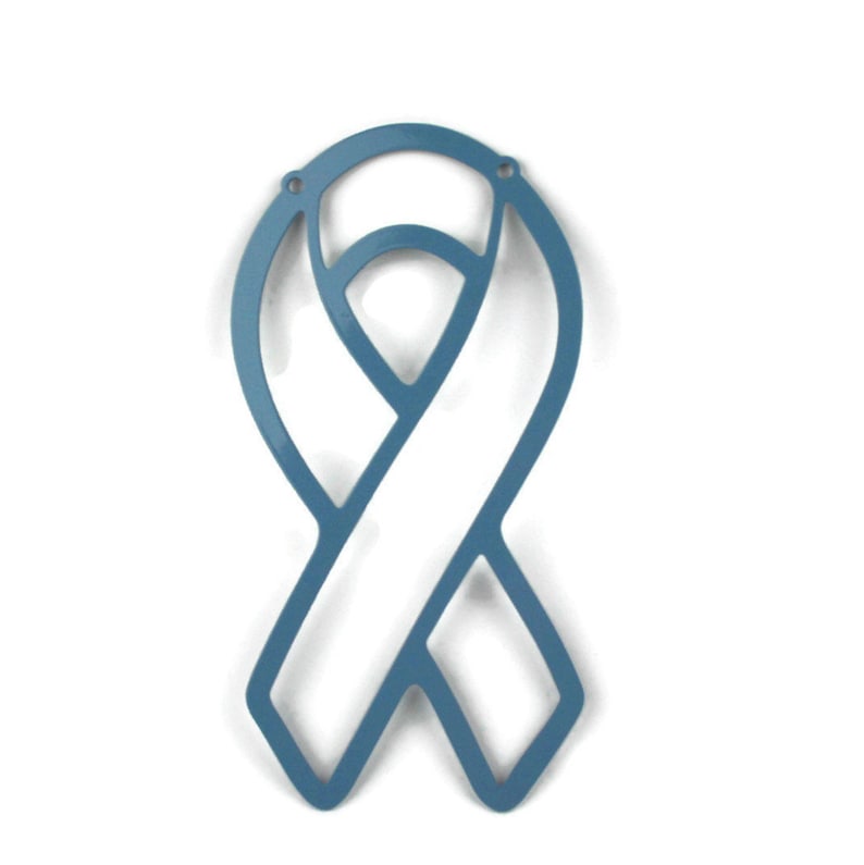 May include: A blue ribbon-shaped ornament with a cutout design. The ribbon has a stylized form with a central band and a looped top. Two small holes are at the top for hanging. The ornament is set against a white background.