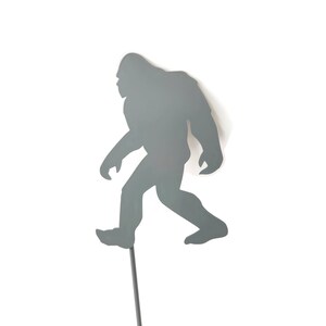 May include: A white ceramic mug with a black handle and the text "But First, Coffee" in a bold, black font. The mug is set against a blurred background, suggesting a cozy setting.