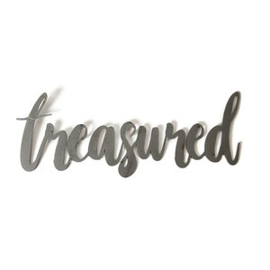 May include: Metal wall decor with the word "treasured" written in a cursive font.