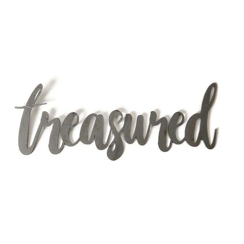 May include: Metal wall decor with the word "treasured" written in a cursive font.