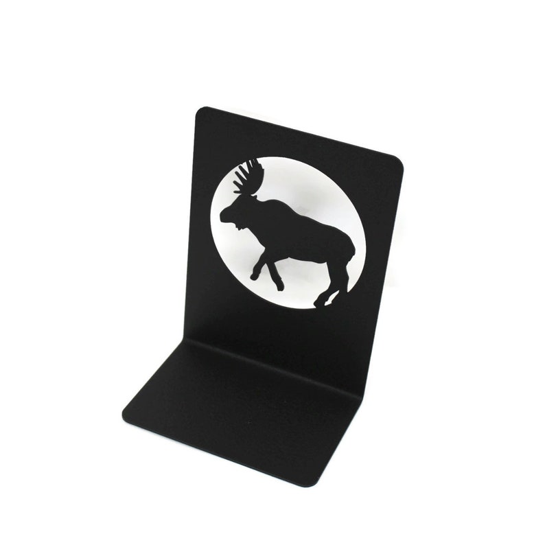 May include: Black metal bookend featuring a silhouette of a moose in a circle. The bookend is designed to hold books upright.