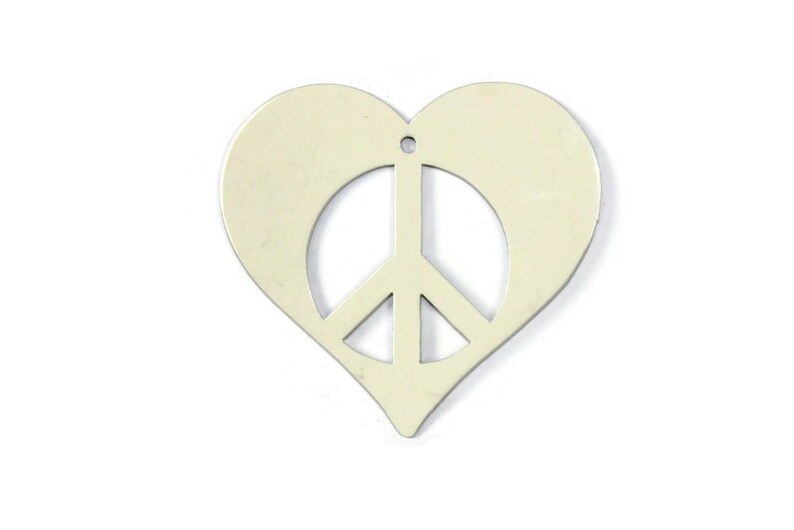 May include: A white metal heart-shaped charm with a peace sign cut out in the center.