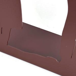 May include: A matte brown metal object featuring a flat base and two vertical, curved side panels that extend upward. The structure has a cutout design, creating a hollow center space between the two side elements, finished in a solid, uniform color.