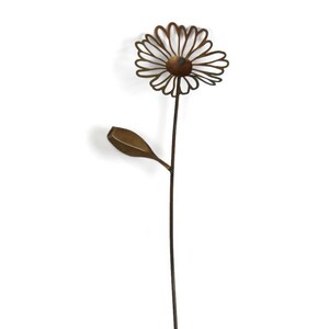 May include: A metal daisy garden stake with a brown stem, a flower head with a circular center, and a single leaf. The flower petals are outlined with thin metal lines. The garden stake is a decorative outdoor accent.