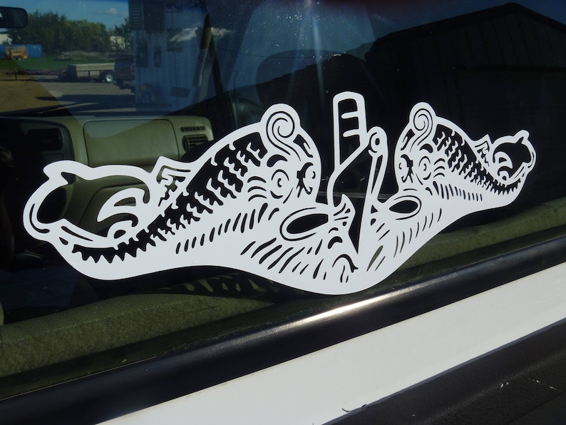 May include: A white vinyl decal of a stylized submarine with a detailed design. The decal is on a car window.