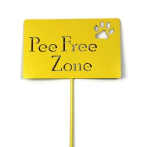 May include: A yellow metal sign with the words "Pee Free Zone" cut out, along with a paw print. The sign is mounted on a yellow stake, designed for outdoor use. The sign is likely for a garden or yard.