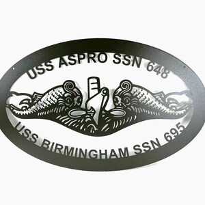 May include: Black metal oval sign with the text "USS ASPRO SSN 648" and "USS BIRMINGHAM SSN 695" and a stylized submarine emblem.