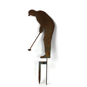 May include: A rusty metal lawn ornament depicting a golfer in mid-swing. The figure is attached to a stake for easy placement in a garden or yard. The golfer is approximately 18 inches tall.