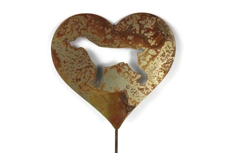 May include: A heart-shaped metal garden stake with a cut-out silhouette of a dog. The metal has a rustic, weathered appearance with shades of brown and gold. The stake is designed for outdoor use.