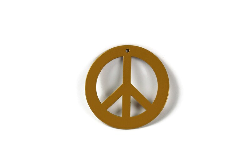 May include: A gold peace sign ornament with a hole at the top for hanging.