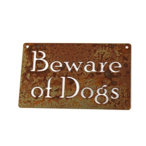 May include: A rusty metal sign with the text "Beware of Dogs" in white lettering.