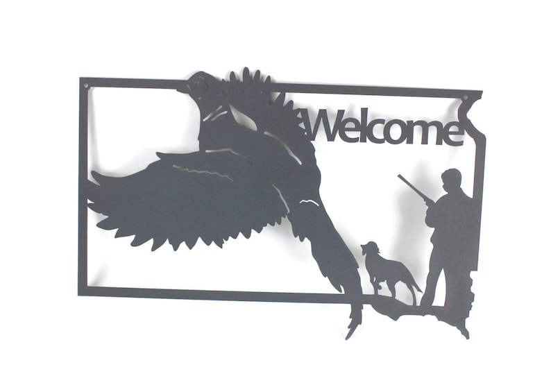 May include: Black metal wall art featuring a flying bird, a hunter with a rifle, and a dog. The word "Welcome" is cut out of the metal. The artwork is in the shape of a state.