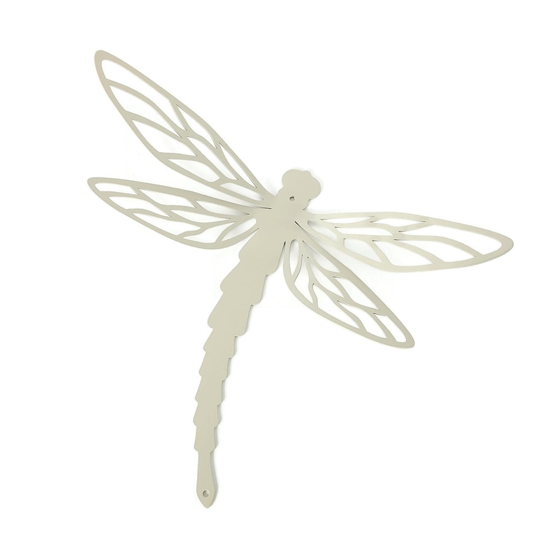 May include: A light beige metal dragonfly wall art. The dragonfly has detailed wing patterns and a segmented body. The wings are outstretched, and the design is cut out, creating an openwork effect. The dragonfly is a decorative item.