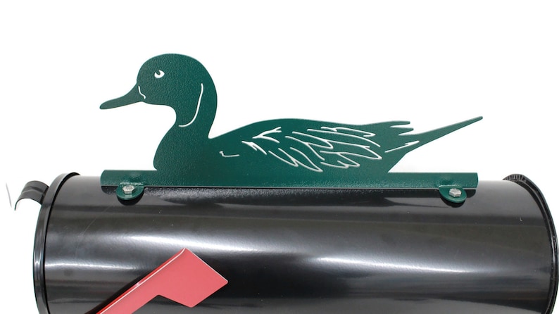 May include: Green metal duck mailbox topper. The duck is in a swimming position with its head turned to the side. The mailbox topper is attached to a black mailbox.