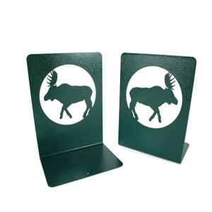 May include: A pair of green metal bookends with a white moose silhouette cutout in a circle on each.