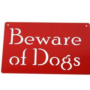May include: Red metal sign with white text that reads "Beware of Dogs".