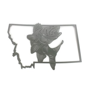 May include: A metal cutout of the state of Montana with a fish jumping out of the outline. The fish is facing right and has a detailed design.