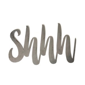 May include: Metal wall decor with the word "Shhh" written in a cursive font.