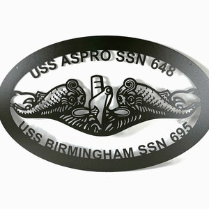 May include: Black metal oval sign with the text "USS ASPRO SSN 648" and "USS BIRMINGHAM SSN 695" around a submarine emblem.