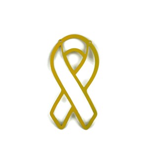 May include: A gold-colored awareness ribbon cutout, featuring a looped design with a central vertical band. The ribbon has two small holes at the top for hanging. The background is plain white.