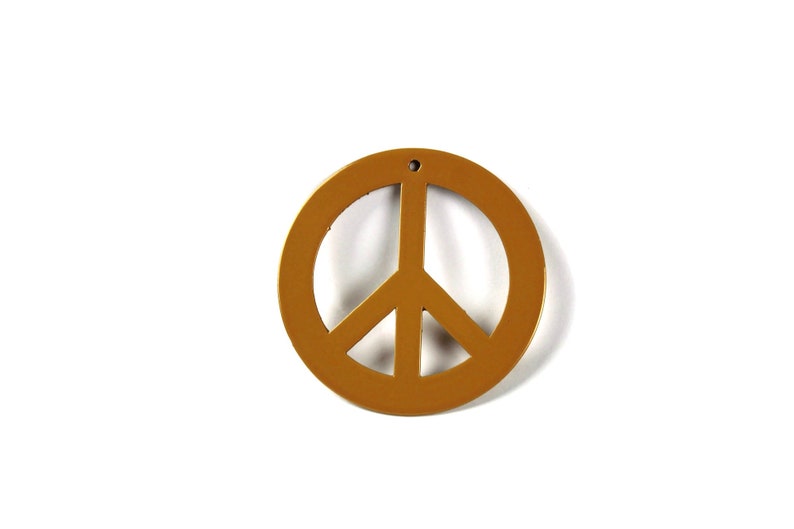 May include: A gold peace sign charm with a hole at the top for hanging.