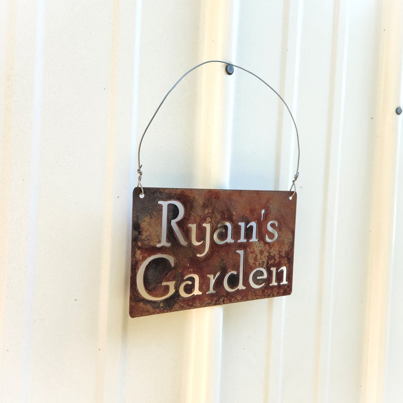 This picture shows what it looks like hanging from a nail or bolt. You can see through the letters on the sign and see the color of the building behind it.
