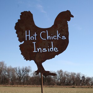 May include: A rusty metal silhouette of a chicken with the words "Hot Chicks Inside" written in white paint.