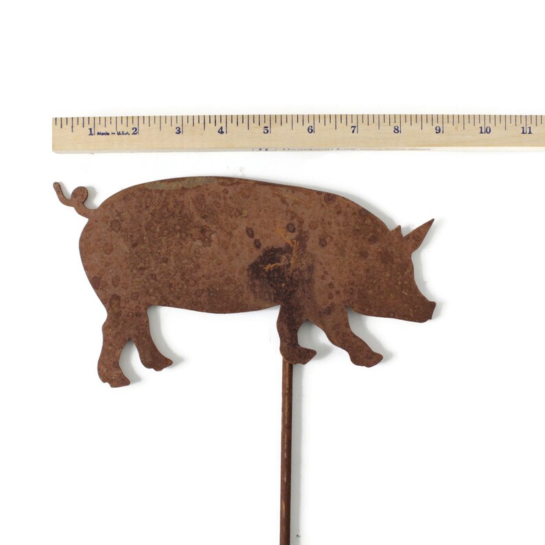 May include: A rusty metal pig silhouette with a long metal stem. The pig is facing right and has a curled tail. The pig is approximately 6 inches long.