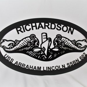 May include: Black metal oval sign with the text "RICHARDSON USS ABRAHAM LINCOLN SSBN 602" and a stylized image of a submarine with two dolphins.