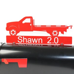Pode incluir: Topper de caixa de correio de metal vermelho com uma silhueta de caminh&atilde;o de plataforma vermelha e o nome "Shawn 2.0" em letras brancas.