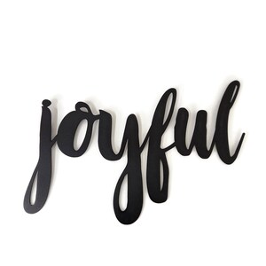 May include: Black metal wall decor with the word "joyful" written in a cursive font.