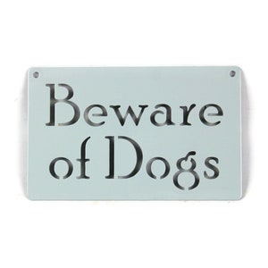 May include: A light blue metal sign with the text "Beware of Dogs" cut out in black.