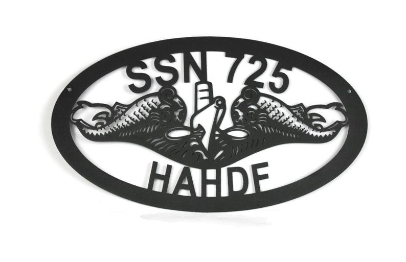 Puede incluir: Un letrero de pared ovalado de metal negro con un dise&ntilde;o recortado de la insignia de guerra submarina, que incluye dos delfines flanqueando la proa de un submarino. El texto SSN 725 est&aacute; arriba y el texto HAHDF abajo en el &oacute;valo.